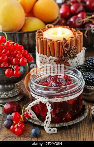 Pots de confiture de fraises de cerise parmi les fruits d'été et d'automne sur une table en bois. Banque D'Images