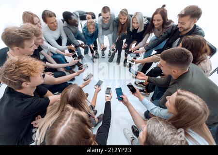 gros plan. groupes de jeunes avec des smartphones assis dans un cercle Banque D'Images