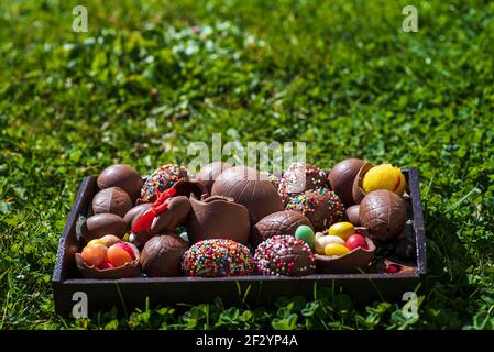 Chocolats œufs de Pâques avec bonbons aux œufs sur un terrain d'herbe dans la cour avec espace de copie Banque D'Images