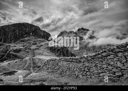 Superbe image paysage noir et blanc d'hiver de Pike latéral vers Langdale pikes avec nuages bas niveau sommets de montagne et brume de moody Banque D'Images