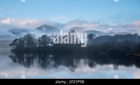 Image de paysage épique regardant à travers Derwentwater dans Lake District vers Catbells a enneigé la montagne avec un épais brouillard qui se balade dans la vallée Banque D'Images