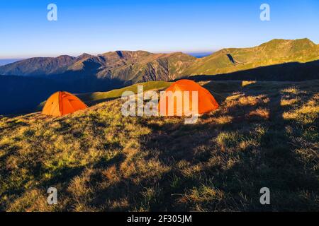 Camping avec tentes colorées sur la crête de montagne. Campgound sauvage dans les montagnes au lever du soleil, Fagaras montagnes, Carpates, Roumanie, Europe Banque D'Images