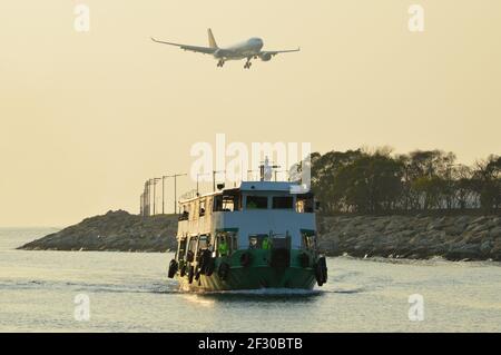 Ferry pour passagers exploité par Fortune Ferry à l'approche de Sha Lo WAN Pier, avec un atterrissage d'avion au-dessus de l'aéroport international de Hong Kong Banque D'Images