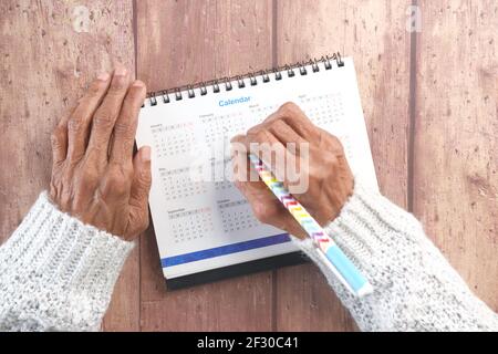 les femmes âgées ont main avec cercle de plume le date sur 2021 calendrier sur fond de bois Banque D'Images