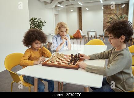 Joueurs. Enfants jouant aux échecs. Petits garçons assis à la table et jouant à l'école d'échecs Banque D'Images