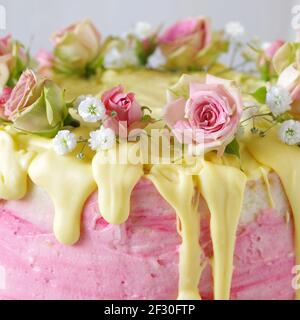 Gâteau de fête à la crème de beurre rose aux fraises avec glaçage au chocolat jaune et roses Banque D'Images