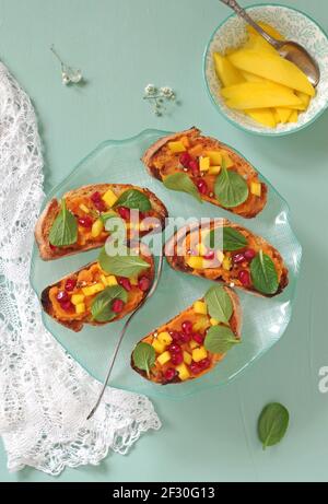 Crostini avec purée de patates douces, mangue, jeunes épinards chinois et grenade Banque D'Images