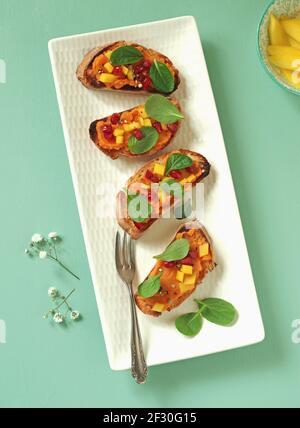 Crostini avec purée de patates douces, mangue, jeunes épinards chinois et grenade Banque D'Images