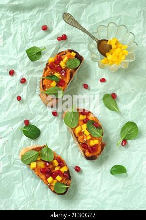 Crostini avec purée de patates douces, mangue, jeunes épinards chinois et grenade Banque D'Images