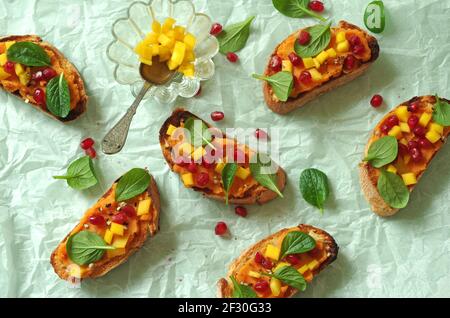 Crostini avec purée de patates douces, mangue, jeunes épinards chinois et grenade Banque D'Images