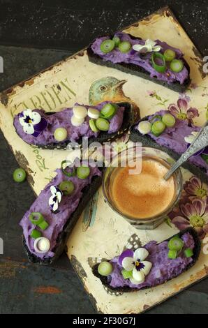 Crostini noire au lilas vitelotte crème de pomme de terre, bulbe d'oignon et pansy à cornes Banque D'Images