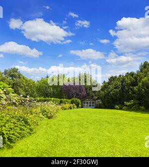 Jardin bien entretenu avec un lit de fleur coloré et un abri de jardin Banque D'Images