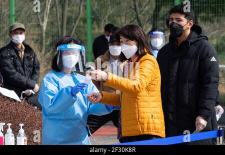 Hwaseong, Corée du Sud. 14 mars 2021. Un travailleur médical demande aux gens de recevoir le test COVID-19 à Hwaseong, dans la province de Gyeonggi, en Corée du Sud, le 14 mars 2021. Les autorités sud-coréennes ont déclaré vendredi qu'elles étendront les règles de distance sociale de niveau 2, la troisième plus élevée parmi le système à cinq niveaux du pays, dans la zone métropolitaine de Séoul pour deux semaines jusqu'en mars 28. Credit: SEO Yu-Seok/Xinhua/Alay Live News Banque D'Images