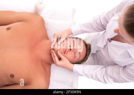 Femme effectuant un massage sur le visage d'un client masculin Banque D'Images