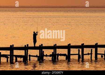 Un homme en silhouette pêche d'un quai au crépuscule à Fairhope, Alabama, USA, le 21 novembre 2020. Banque D'Images