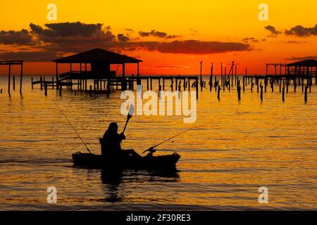 Un kayakiste prend le coucher du soleil tandis que le crépuscule s'installe au-dessus de Mobile Bay, vu de Fairhope, Alabama, États-Unis, le 22 novembre 2020. Banque D'Images