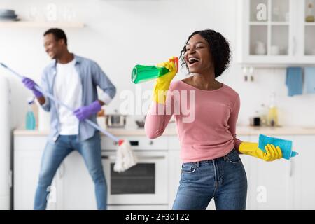 Femme noire s'amusant avec son petit ami tout en nettoyant la cuisine Banque D'Images