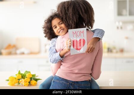 Bonne fille noire saluant maman avec tulipes et carte Banque D'Images