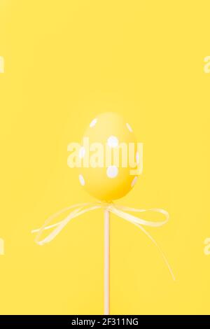Œuf de Pâques jaune sur bâton sur fond jaune. Carte de vœux de Pâques avec espace pour copier. Banque D'Images