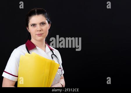 portrait de femme médecin avec stéthoscope et dossier de documents sur fond sombre Banque D'Images