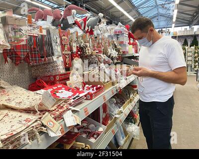 Grand assortiment de jouets de Noël sur le comptoir du supermarché. L'homme dans le masque médical choisit des jouets de Noël Banque D'Images