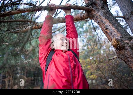 Femme active senior heureuse de pendre de l'arbre dans la forêt Banque D'Images
