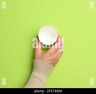 Une femme tient une tasse jetable en papier vide sur fond vert Banque D'Images