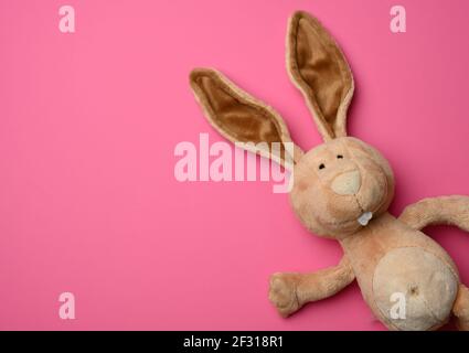 Adorable lapin en peluche avec de longues oreilles, fond rose pâques Banque D'Images