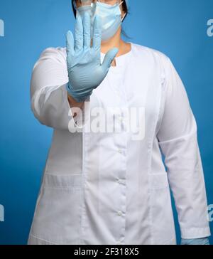 Médecin en manteau médical blanc et gants en latex bleu montre stop geste, concept de garder une distance sûre Banque D'Images