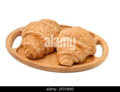 Deux croissants cuits au four se trouvent sur un plateau en bois, nourriture isolée sur fond blanc, gros plan Banque D'Images