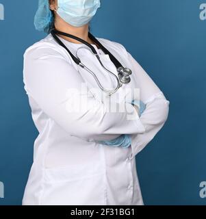 Femme médecin dans une robe médicale blanche se tient sur un fond bleu, Banque D'Images