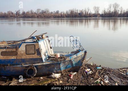 Vieux bateau de pêche coincé dans la poubelle sur une plage sale, problèmes de pollution Banque D'Images