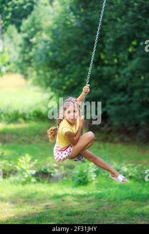 Portrait de la belle petite fille est balançant et jouant au parc d'été. Mise au point douce Banque D'Images