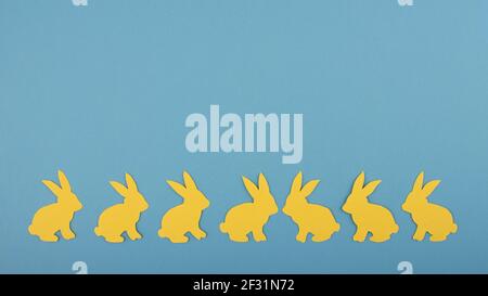 Concept joyeuses Pâques. Bannière large avec lapin en papier jaune sur fond bleu. Copier l'espace. Coupe de papier. Banque D'Images