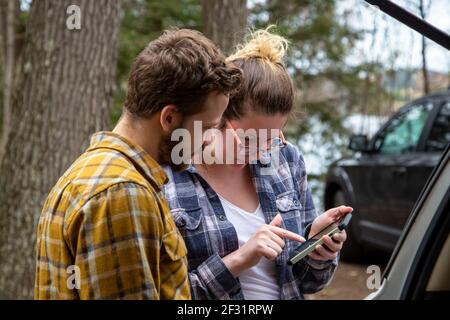 les voyageurs consultant le gps et guide sur un smartphone en plein air au cottage Banque D'Images