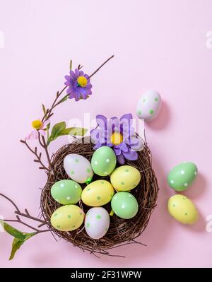 Modèle de carte de vœux Joyeux Pâques. Célébration et décoration de vacances de religion chrétienne. Oeufs de Pâques pastel couleurs dans un nid sur fond rose, à Banque D'Images