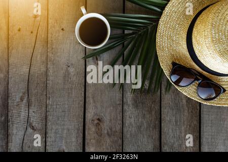 Voyage, concept de vacances. Chapeau, feuille de palmier, tasse à café, lunettes sur fond de bois. Détendez-vous. Photo de haute qualité Banque D'Images