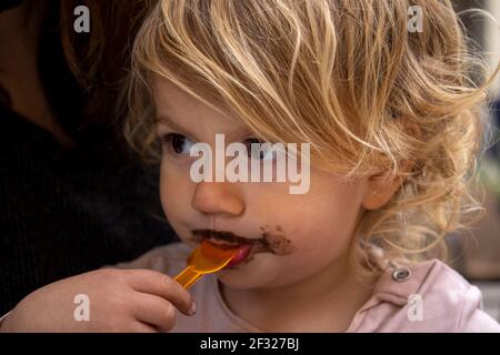 Bébé fille mangeant de glace au chocolat Banque D'Images