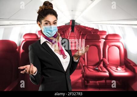 Un beau gardien de vol avec foulard multicolore et masque, illustre l'intérieur d'un avion. Photo parfaite pour les voyages, les vacances et le travail Banque D'Images