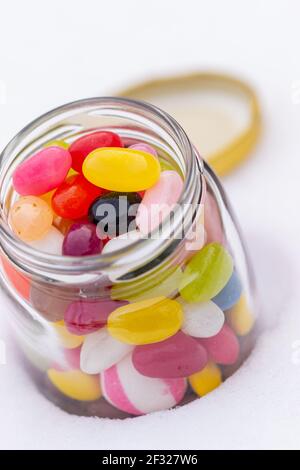 Jelly beans colorés dans un pot isolé sur blanc. Banque D'Images