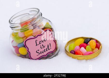 Jelly beans colorés dans un pot isolé sur blanc. Banque D'Images