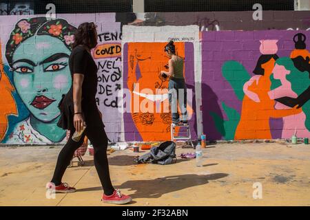 Barcelone, Espagne. 14 mars 2021. Une femme marche à côté d'un démonstrateur graffiti écrivant sur le mur pendant la journée de l'art féminin.les collectifs féministes latino-américains ont organisé une journée d'art féminin avec des peintures, graffiti, musique et présentations aujourd'hui à Barcelone. (Photo de Thiago Prudencio/SOPA Images/Sipa USA) crédit: SIPA USA/Alay Live News Banque D'Images