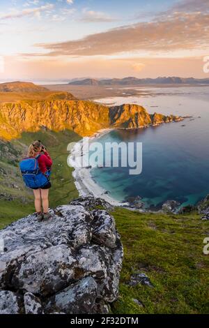 Randonneur debout sur un éperon rocheux surplombant la plage et la mer, sommet de la montagne de Matinden, près de Stave, Nordland, Norvège Banque D'Images