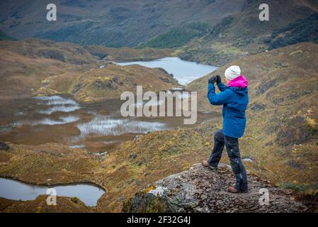 Une jeune femme en action de photographier la beauté de la nature dans le parc national de cajas près de Cuenca, en Equateur, avec vue panoramique sur les lacs, les ruisseaux, la vallée Banque D'Images