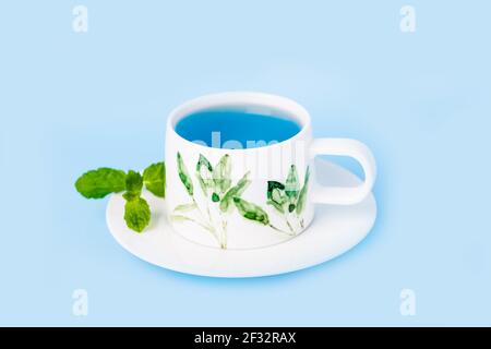 Tasse en porcelaine de thé biologique de fleur de pois bleu papillon avec feuille de menthe Banque D'Images