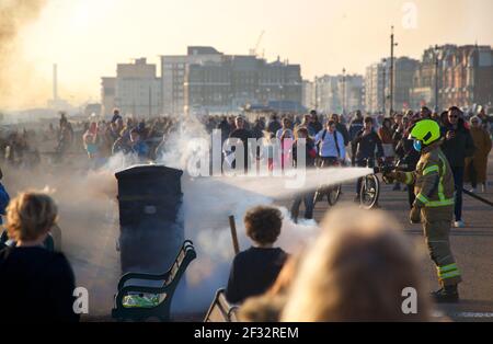 La brigade de pompiers locale assiste à un incendie sur la promenade Hove. Pompier éteignant un incendie dans un casier public avec des spectateurs. Brighton & Hove, East Sussex, Angleterre Banque D'Images