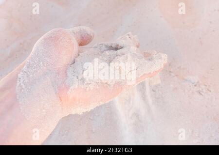 La main du gars prend ou touche le sable blanc de plage de près. Banque D'Images