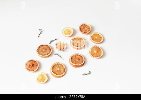 Composition d'oranges entières fraîches et coupées en tranches sanglantes avec de l'herbe de thym isolée sur fond de table blanche. Motif de fruits. Concept alimentaire. Été Banque D'Images