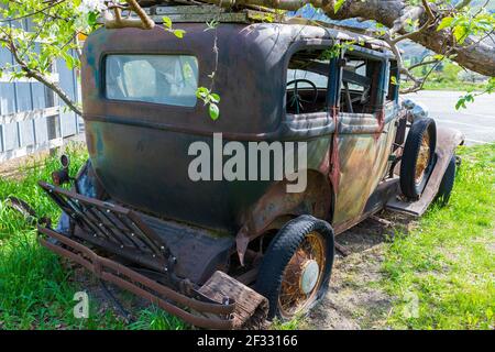 Une voiture ancienne abandonnée sous un arbre Banque D'Images