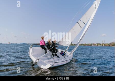 Papa et ses deux filles sont sorties sur un yacht sur la rivière pour naviguer le long de la ville et enseigner aux filles à conduire un yacht sportif. Banque D'Images